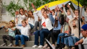 Rock the Riverway performing at the concert, while seated in front of a tent, arms outstretched